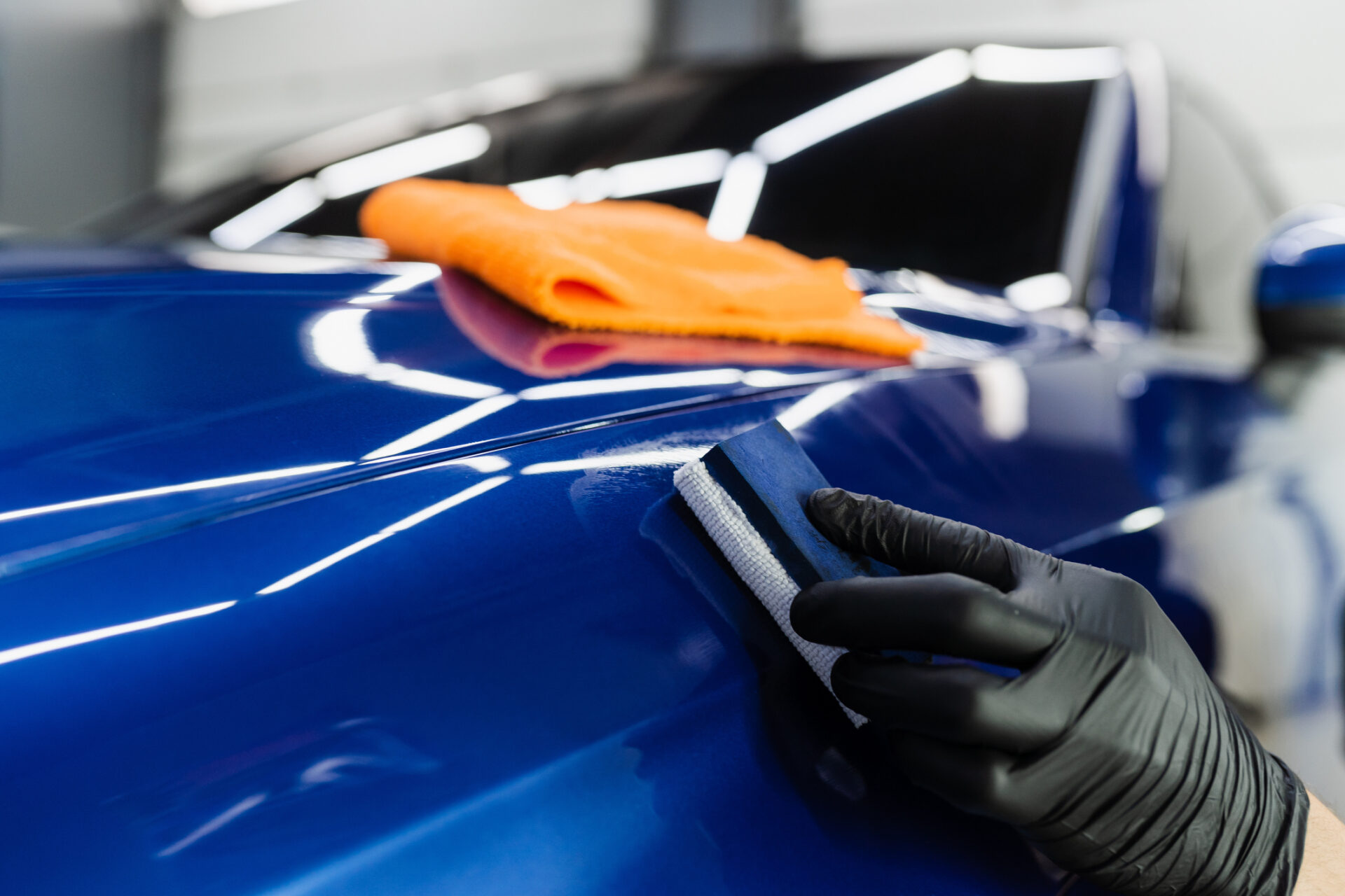 process of applying ceramic protective coat on body car using sponge in detailing auto service. car service worker apply ceramic coating to protect the car body from scratches.